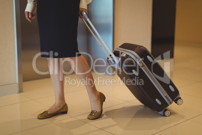 Low section of businesswoman with luggage