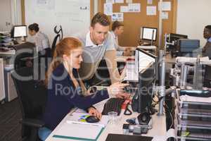 Young businesswoman discussing with male colleague while working in office