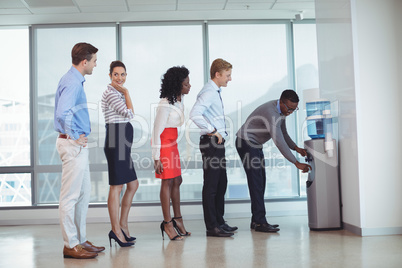 Business people standing by water cooler at office