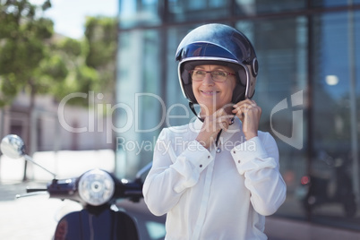 Businesswoman fastening helmet