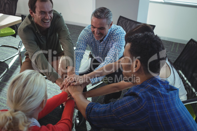 Happy business colleagues stacking hands at office