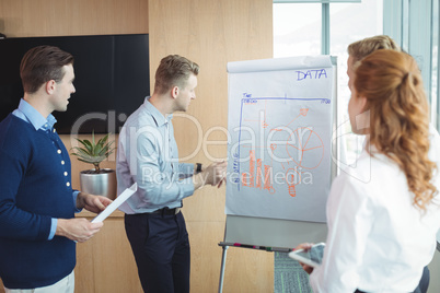 Young businessman discussing over whiteboard with team