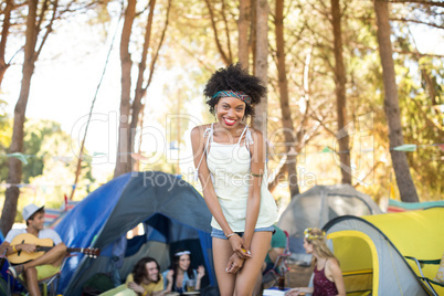 Portrait of smiling young woman standing with friends sitting in background