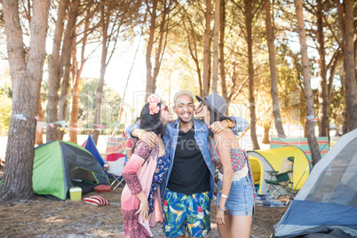 Females kissing male friends standing at campsite