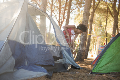 Young woman setting up tent on field