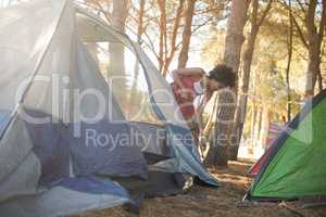 Young woman setting up tent on field