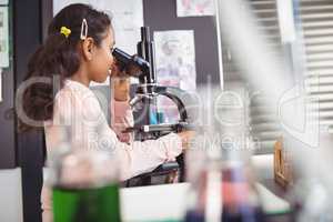 Side view of elementary student using through microscope at laboratory