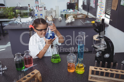 High angle view of elementary student examining blue chemical in flask at laboratory
