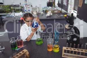 High angle view of elementary student examining blue chemical in flask at laboratory