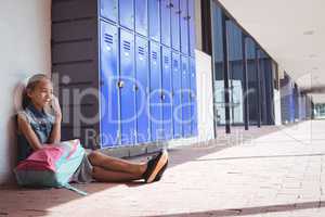 Elementary student talking on mobile phone by lockers