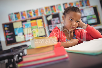Thoughtful schoolgirl sitting at desk