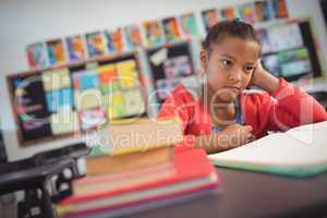 Thoughtful schoolgirl sitting at desk