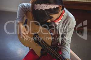 High angle view of girl practicing guitar
