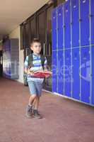 Full length of boy carrying books in corridor