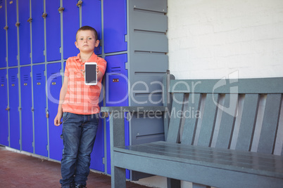 Portrait of boy showing mobile phone while leaning on lockers