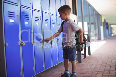 Boy locking locker while wearing bag