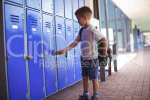Boy locking locker while wearing bag