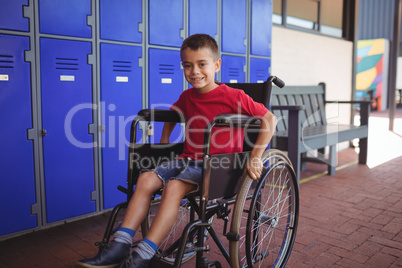 Portrait of boy sitting on wheelchair in corridor