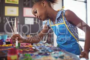 Focused elementary girl painting at desk