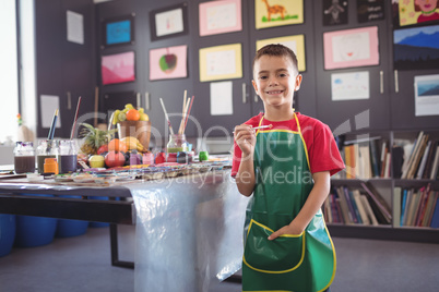 Portrait of smiling boy standing by desk