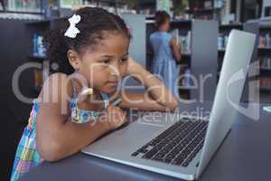 Concentrated girl looking at laptop in library