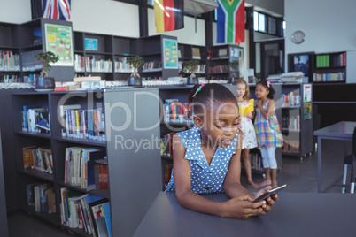 Girl using cellphone at desk in library