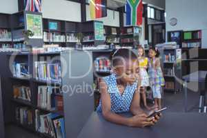 Girl using cellphone at desk in library