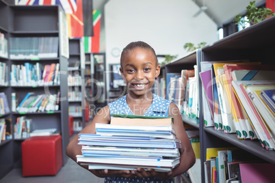 Smiling girl carrying books in library