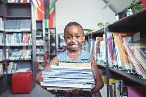 Smiling girl carrying books in library