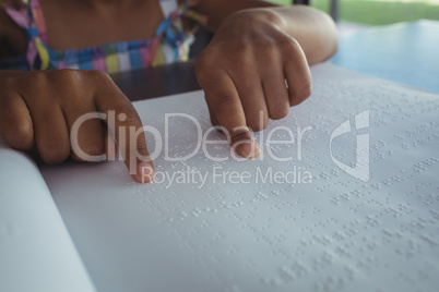 Cropped hands of girl reading braille