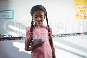 Girl using mobile phone against wall in school