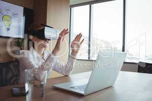 Businesswoman using virtual reality technology at desk