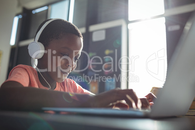 Close up of boy listening music while using laptop