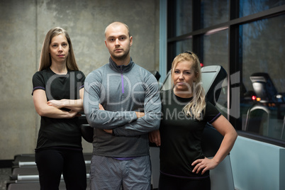 Portrait of friends standing against treadmills