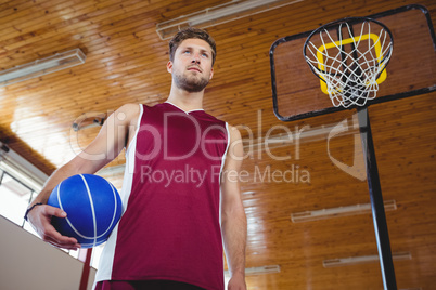 Thoughtful male basketball player with hand on hip