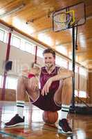 Portrait of male basketball player sitting on ball