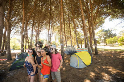 Friends taking selfie with selfie stick at campsite