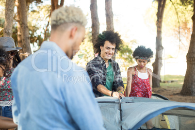 Smiling man with friends setting up tent