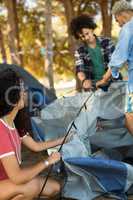 Young woman with male friends setting up tent