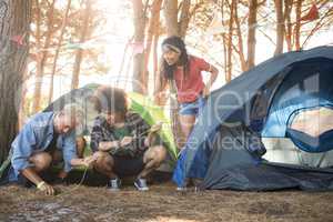 Young friends setting up tent at forest