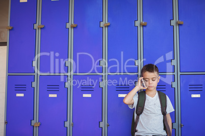 Boy talking on mobile phone against lockers