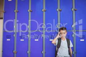 Boy talking on mobile phone against lockers