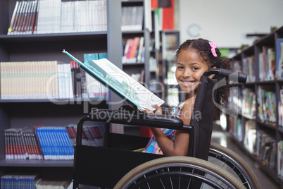 Smiling girl with book on wheelchair