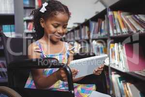Girl on wheelchair using digital tablet in library