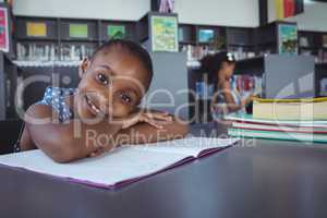 Portrait of girl leaning on book in library
