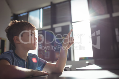 Boy pointing while sitting at desk