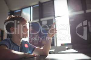 Boy pointing while sitting at desk
