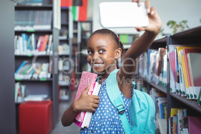 Smiling girl taking selfie in library