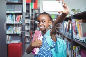 Smiling girl taking selfie in library