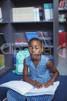 Girl reading braille in library